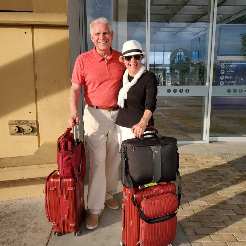 A man and woman standing next to luggage.