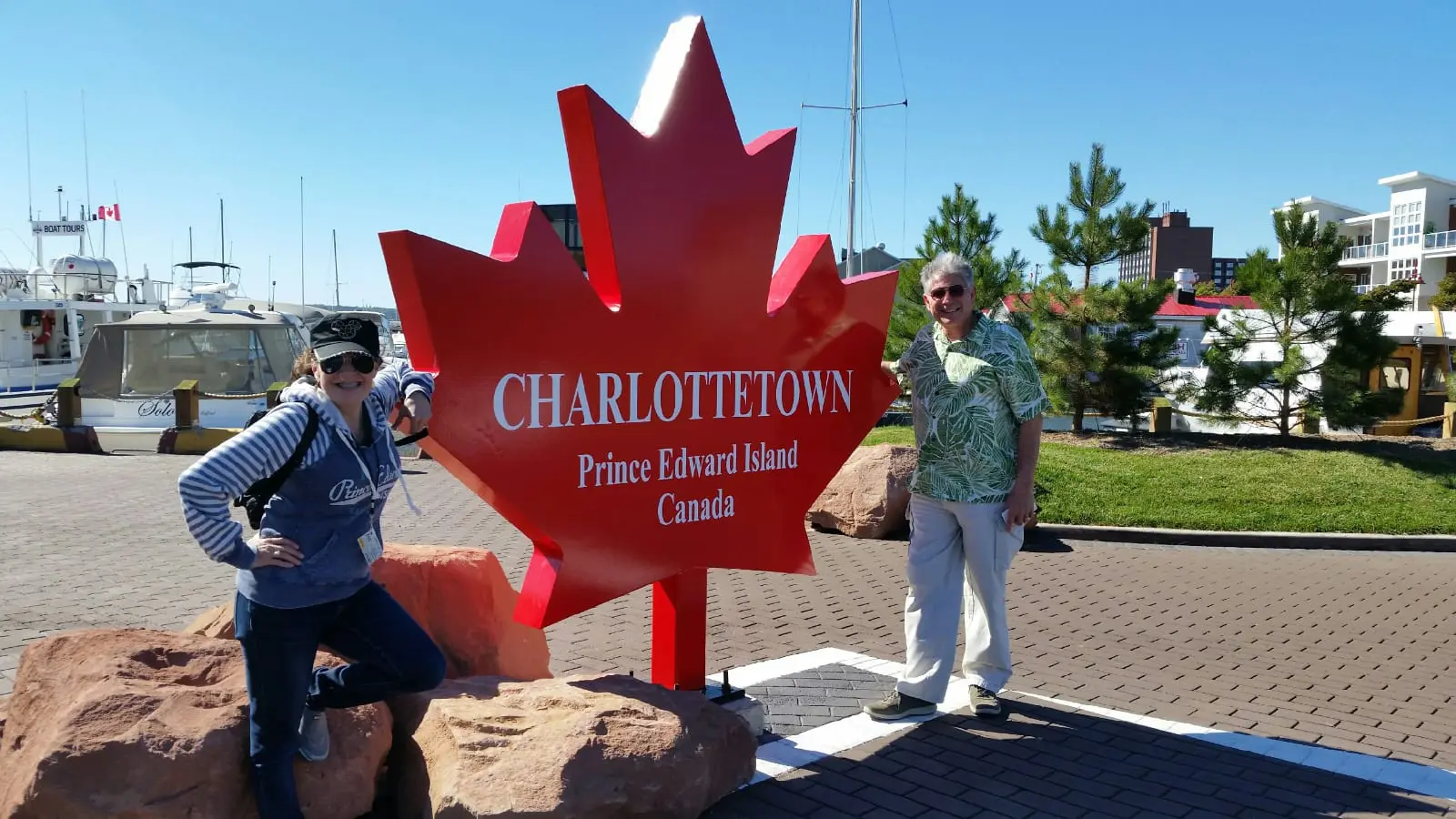 Two people standing in front of a large red leaf.