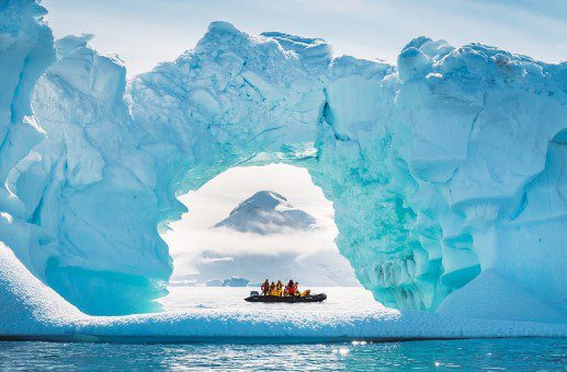 A boat is in the water near an ice arch.