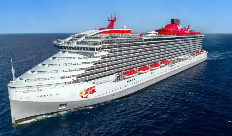 A large cruise ship in the ocean with red and white trim.