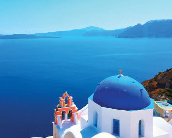 White church with blue dome overlooking the sea.