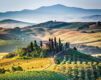 Tuscan countryside with farmhouse and rolling hills.