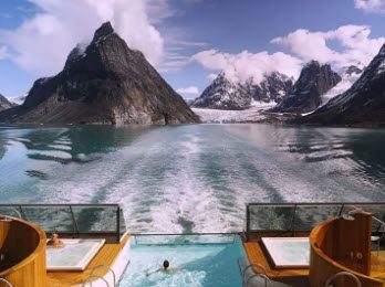 A boat with two people in it and mountains behind them