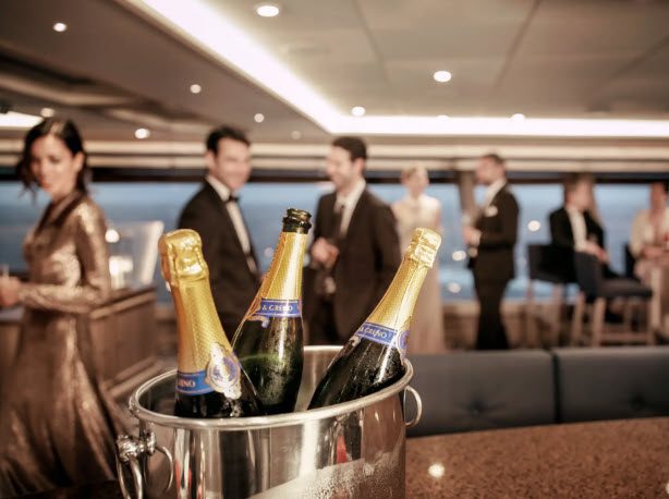 A group of people standing around a room with champagne.