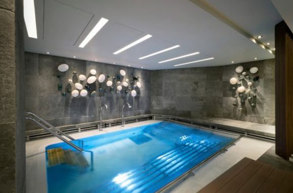 Indoor pool with blue water and white ceiling lights.