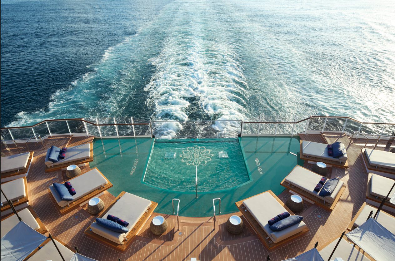 A ship pool with loungers and ocean views.